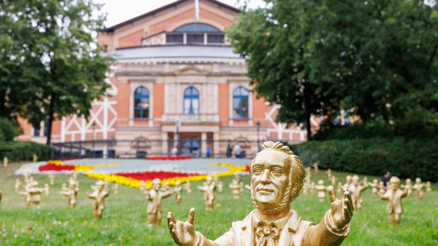 Bayern, Bayreuth: Goldfarbene Wagner-Figuren des Konzeptkünstler Ottmar Hörl stehen im Rahmen der Kunstinstallation «You're welcome» vor dem Festspielhaus vor Beginn der Bayreuther Festspiele. 