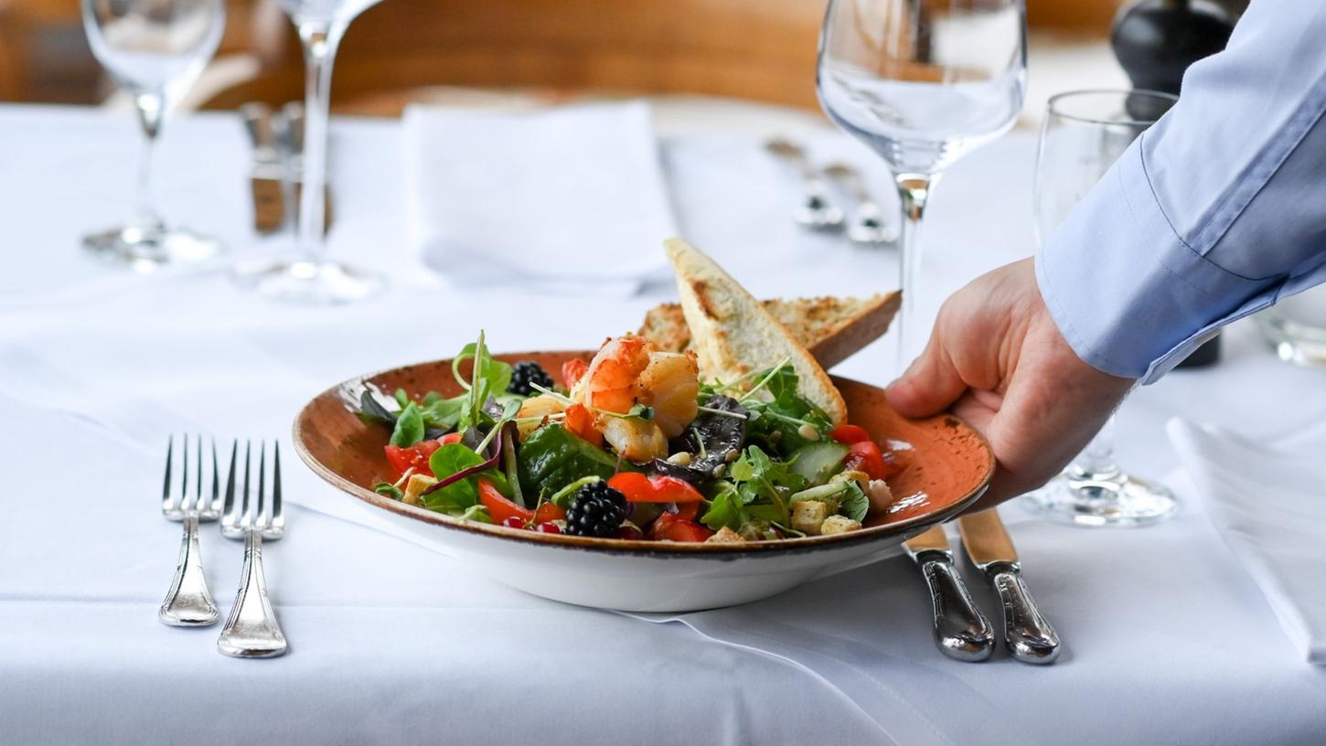 Ein Kellner serviert einen Salatteller in einem Restaurant. 