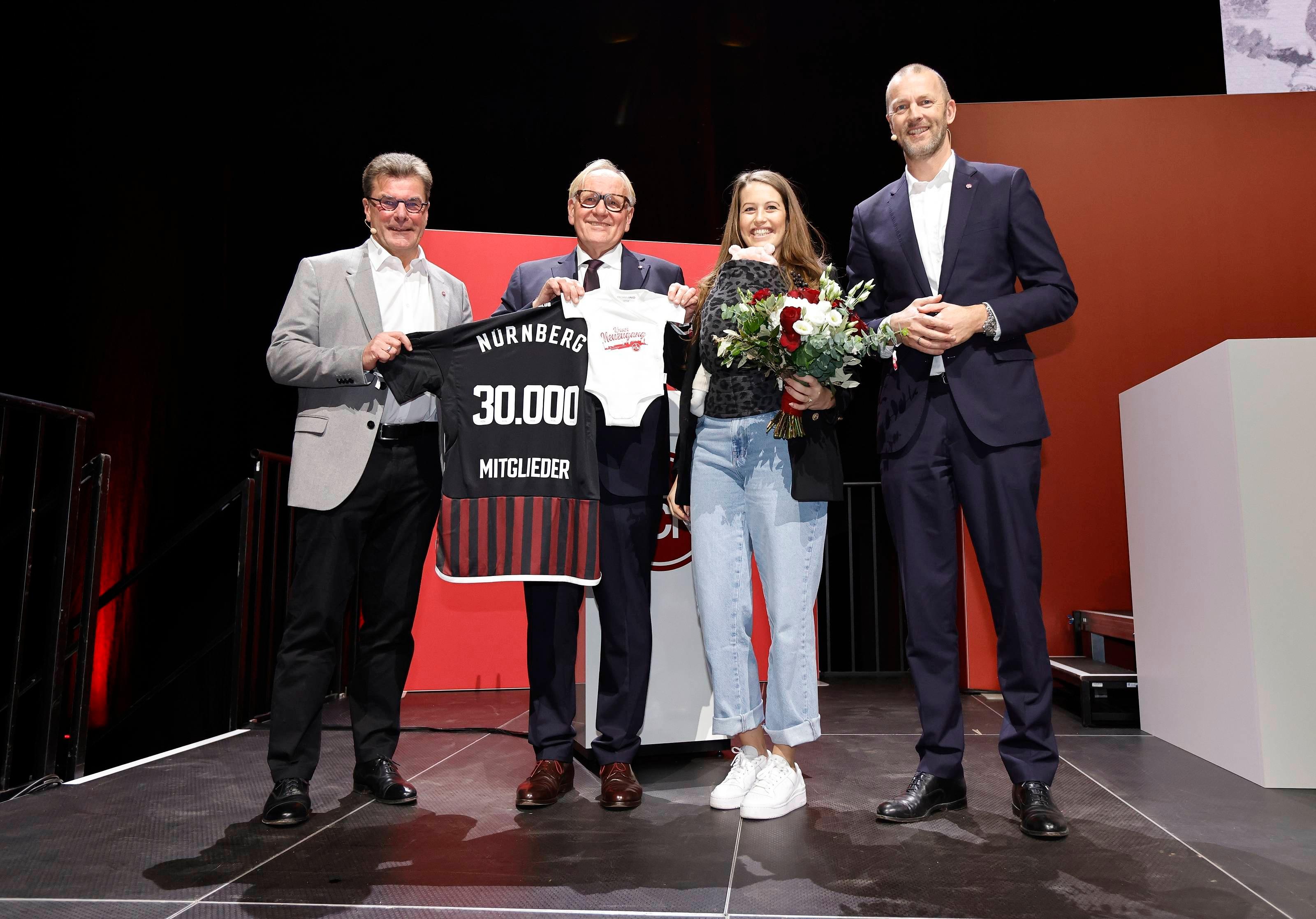 Das 30.000. Mitglied des FCN ist eine Frau - und kam nicht allein nun auf das Podium. Jana Strauch hat ihr frischgeborenes Kind im Tragetuch dabei.