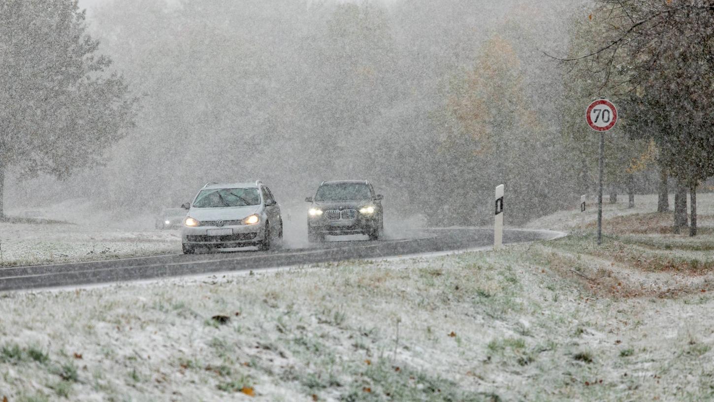 Zwei Autos fahren während Schneefall: Der Wintereinbruch sorgt für zahlreiche Unfälle in Franken.