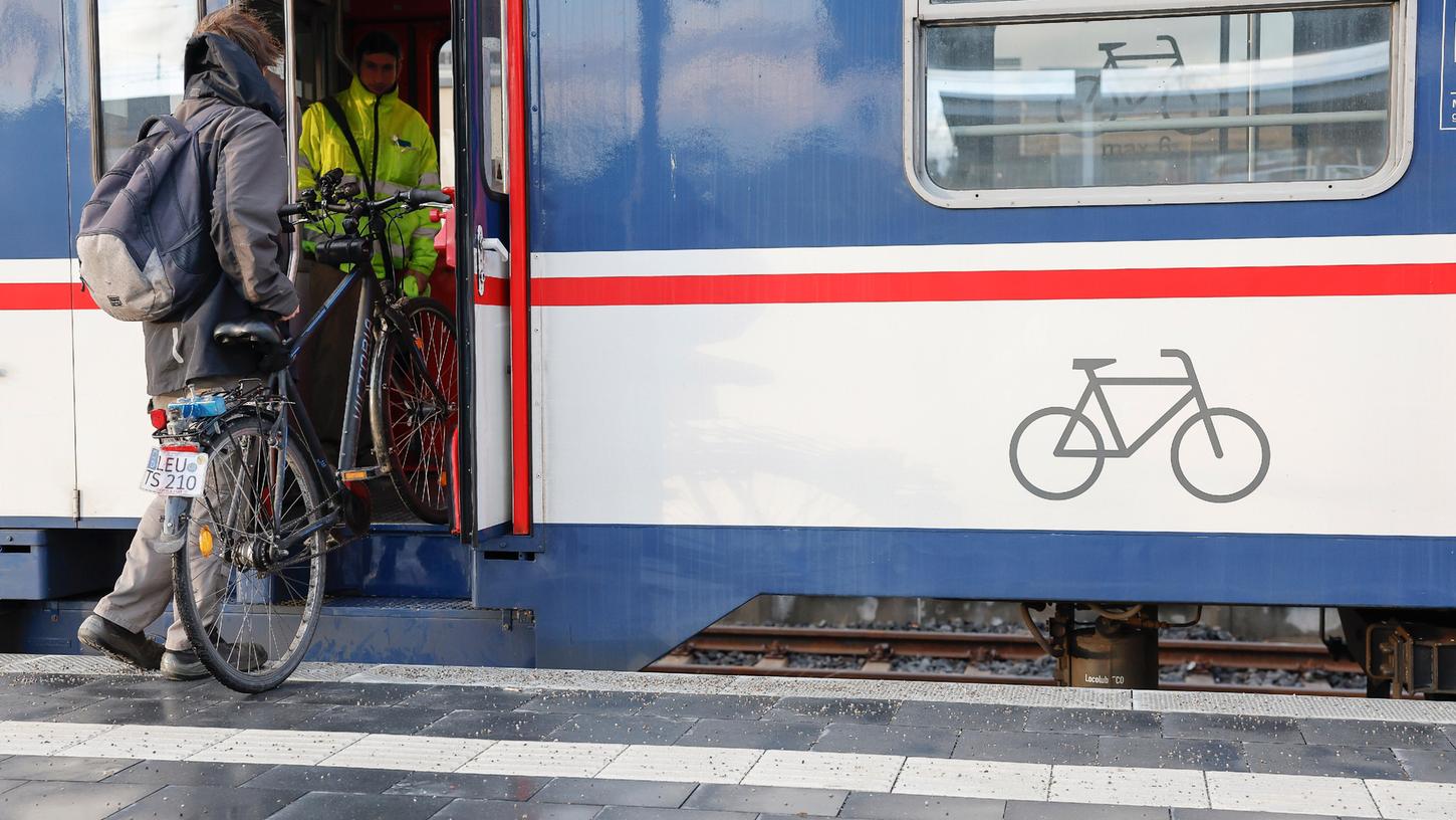 Ein Mann muss sein Fahrrad trotz Barrierefreiheit die letzte Stufe in den Zug heben.