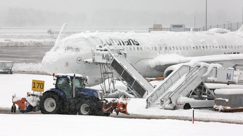 Die Flugzeuge sind von Schnee und Eis bedeckt. Ein Räum- und Streufahrzeug fährt im Schneetreiben auf dem Flughafen an einer Lufthansa-Maschine vorbei. Morgen soll der Betrieb ab 6 Uhr wieder aufgenommen werden.