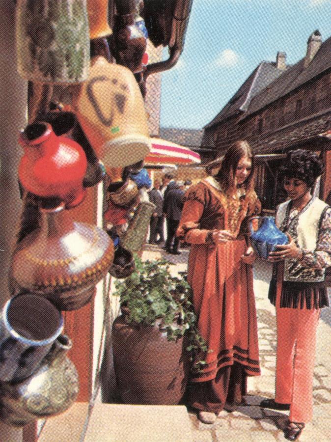 Eine junge Frau im Beratungsgespräch mit einer Touristin, um 1977. Die historisierende Gewandung des Personals war damals im Handwerkerhof üblich.