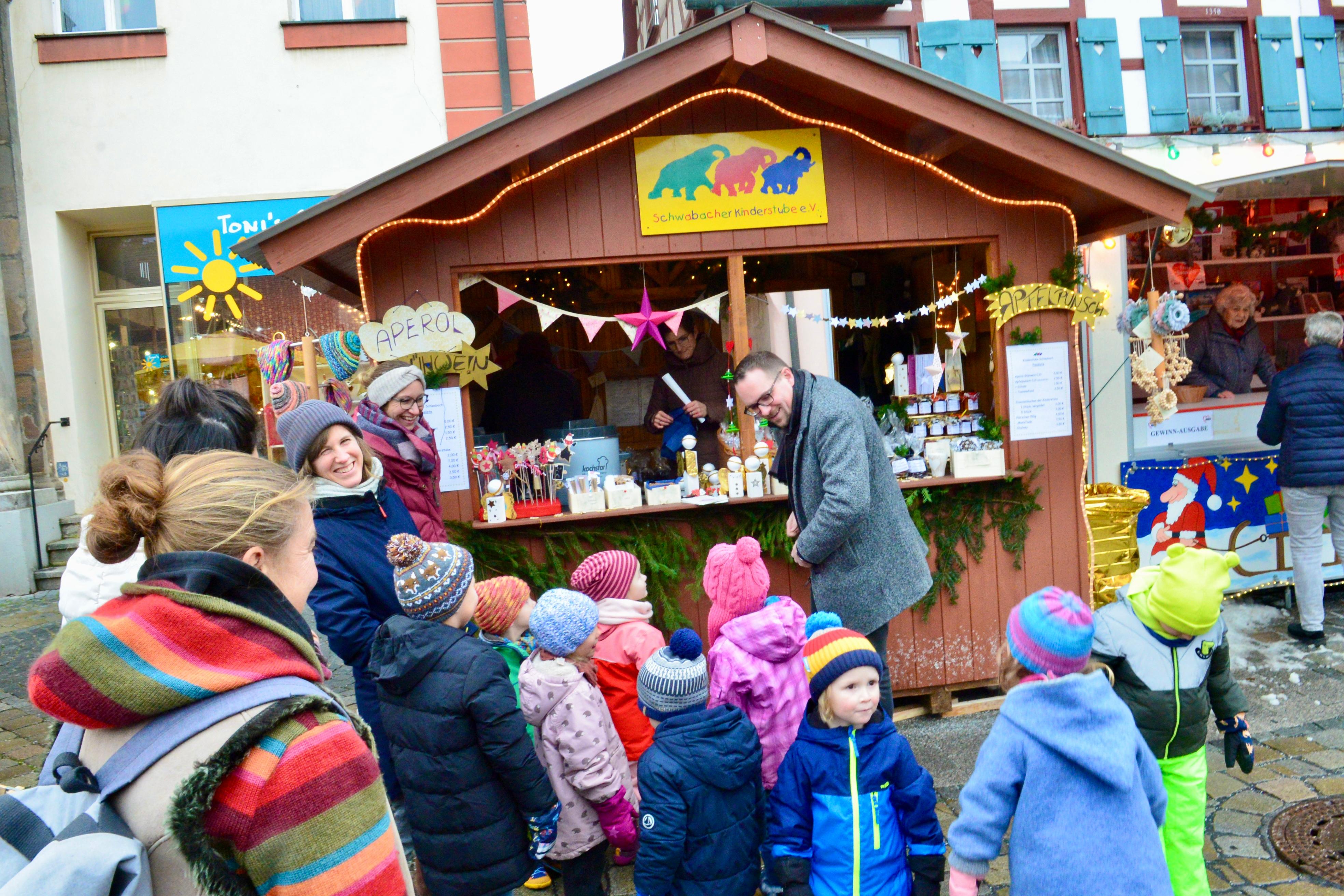 Der Stand der Schwabacher Kinderstube erhielt bald nach dem Auftakt einen Kontrollbesuch. Etwa zehn Kindergartenkinder samt Erzieherinnen und einigen Eltern machten vor dem Bummel über den Weihnachtsmarkt dort halt und präsentierten sich mit selbstgebastelten Kerzen. Zugleich stießen sie auf den Oberbürgermeister: Peter Reiß wollte sich auf dem Weihnachtsmarkt zu Füßen seines Büros Inspirationen für seine Weihnachtsgeschenke holen.
