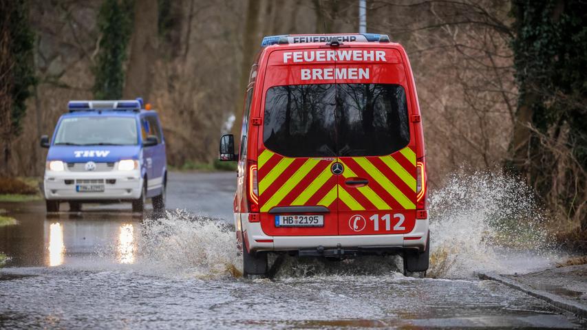 Fahrzeuge von Technischem Hilfswerk und der Feuerwehr begegnen sich auf einer teilweise überfluteten Straße nahe der Wörpe in Lilienthal. 
