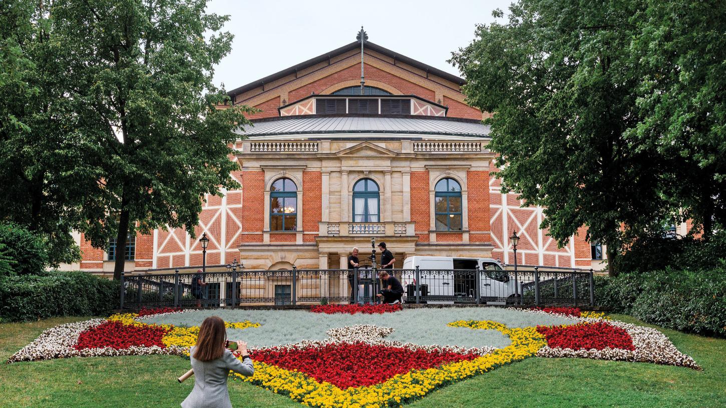 Eine Frau fotografiert die Blumen und das Bayreuther Festspielhaus. 