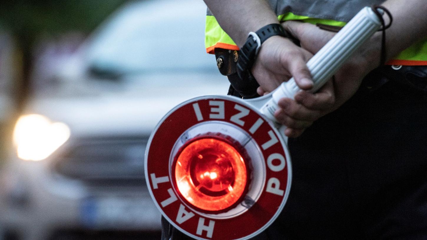 Ein Polizist hält bei einer Verkehrskontrolle eine Winkerkelle in der Hand: Symbolbild. 