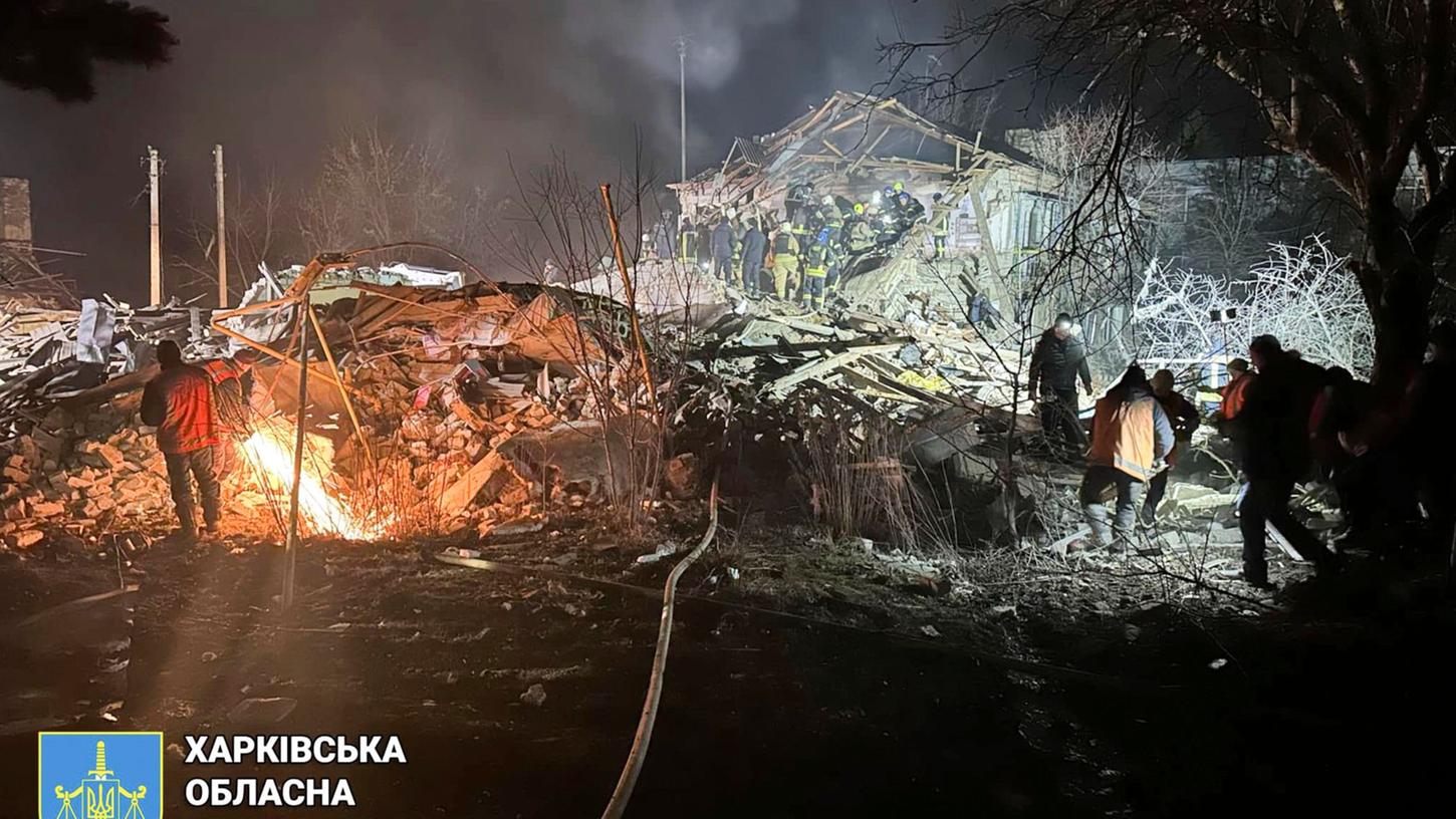 Feuerwehrleute untersuchen in der Region Charkiw die Trümmer eines zerstörten Wohnhauses.