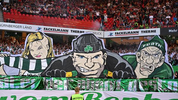 Wenig einladend sehen die Gesichter aus, die der Fürther Anhang im Stadion des Nachbarn präsentiert. "Je später der Abend, desto schöner die Gäste", lautet die Botschaft der Gästefans.