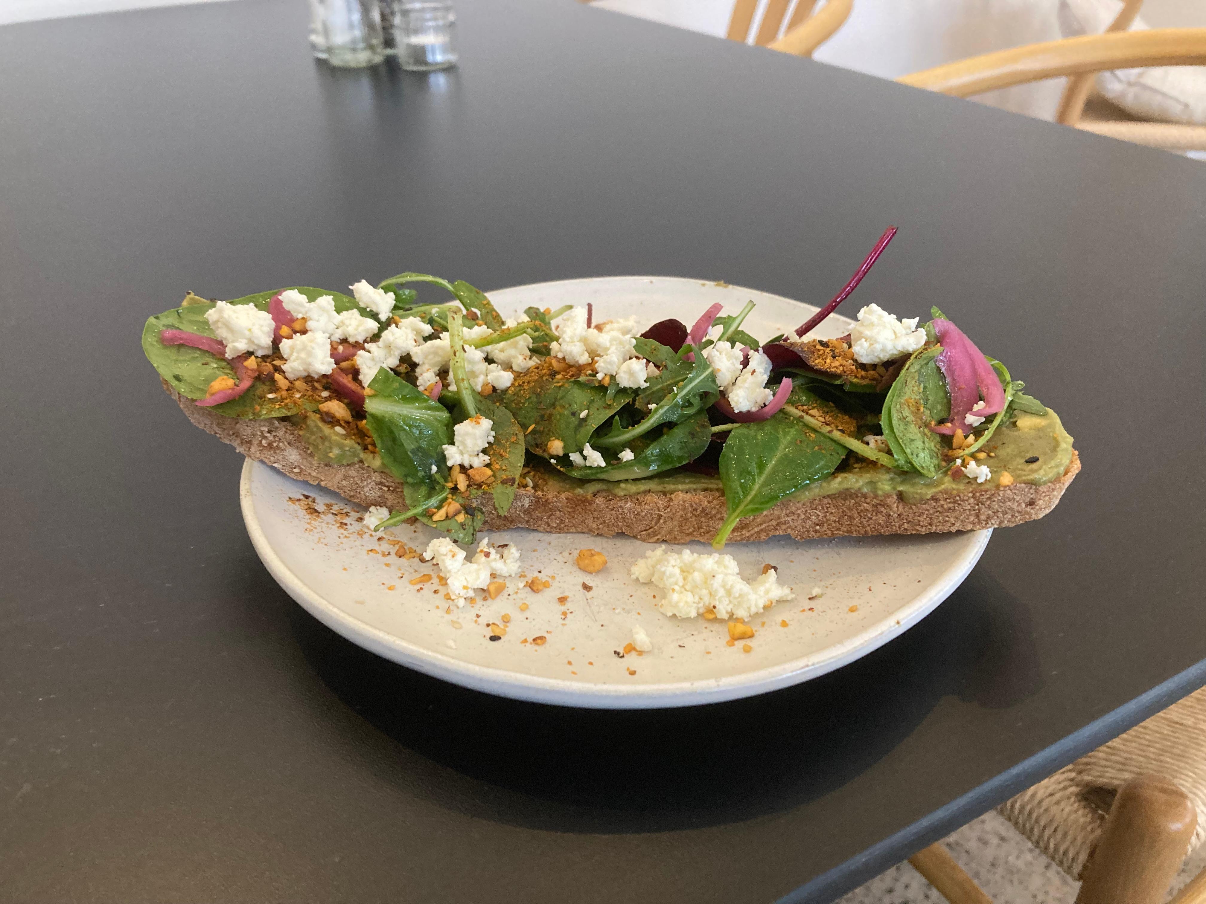 Das klassische Avocado-Brot mit dem besonderen Twist: Avocado, Feta, hausgemachte pinke Zwiebel-Pickles, frischer Pflücksalat und Dukkah auf frischem Sauerteigbrot.