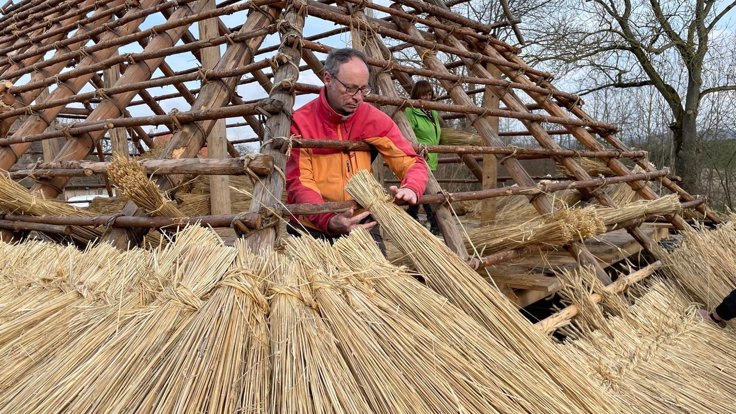 Der Museumsleiter des Oberfränkischen Bauernhofmuseums Kleinlosnitz, Bertram Popp, beim Einsetzen von Stroh-Schauben in das Dach eines Gebäudes im Fränkischen Freilandmuseum in Bad Windsheim.