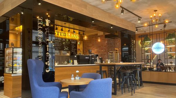 Eingerahmt von schwarzen Säulen, auf denen groß "Fresh Artisan Coffee" steht, ist die Theke des Cafés.