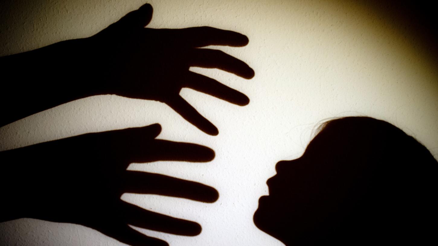 Schatten von Händen einer erwachsenen Person und dem Kopf eines Kindes an der Wand eines Zimmers.