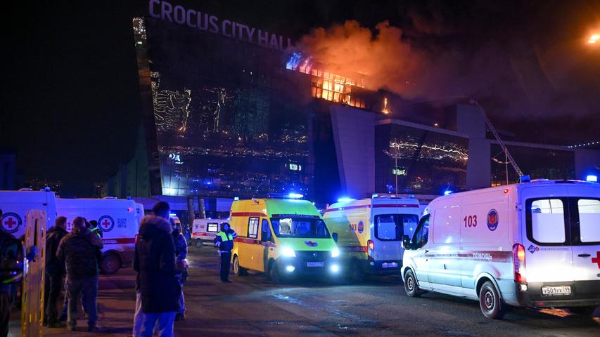 Krankenwagen parken in der Nähe des brennenden Gebäudes des Crocus City Hall am westlichen Rand von Moskau.