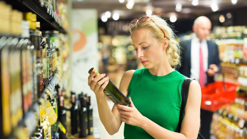Eine Frau sieht sich beim Einkaufen eine Ölflasche genauer an (Symbolbild).