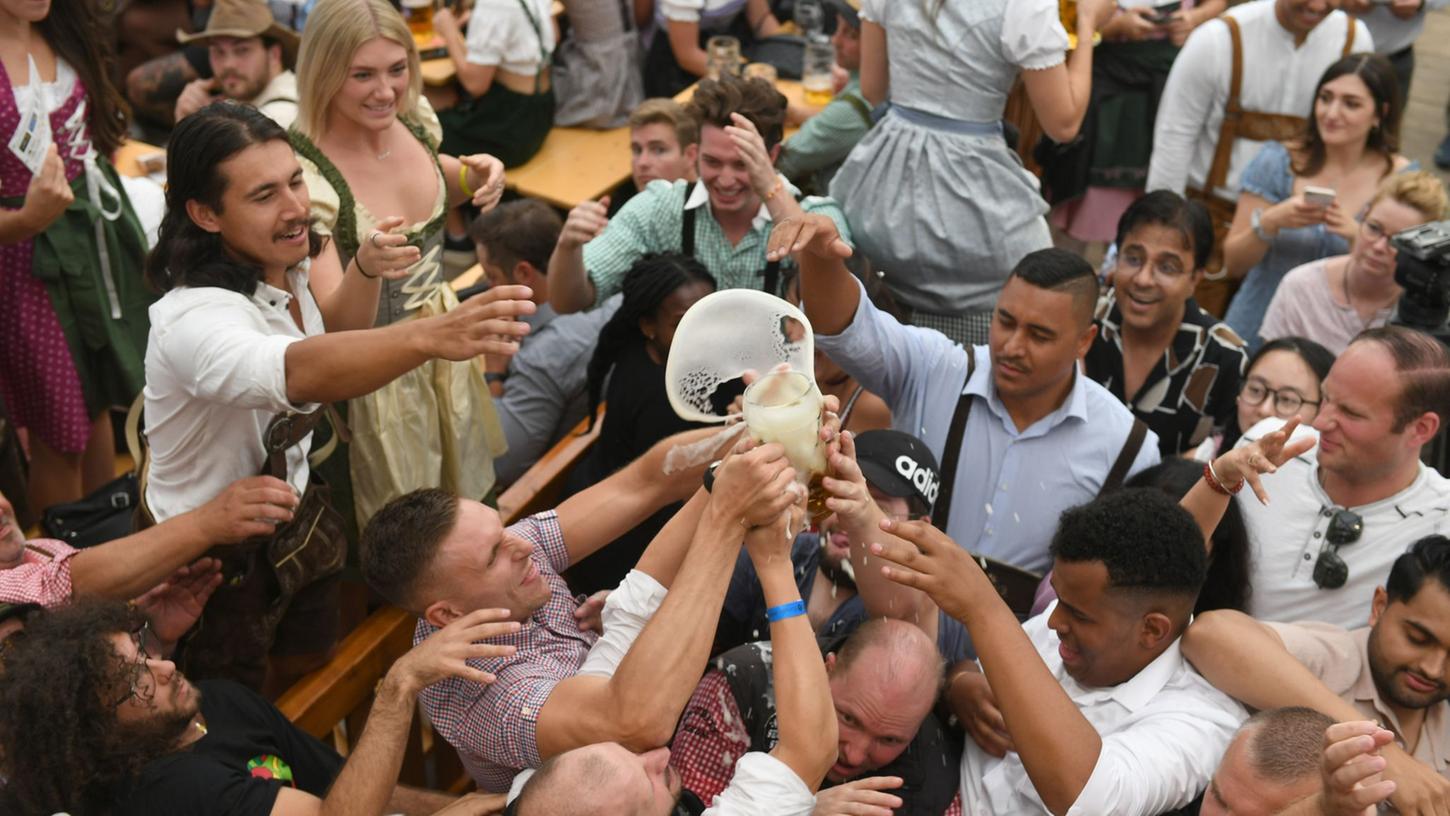 Gäste ringen im Hofbräuzelt um eine Maß Bier.