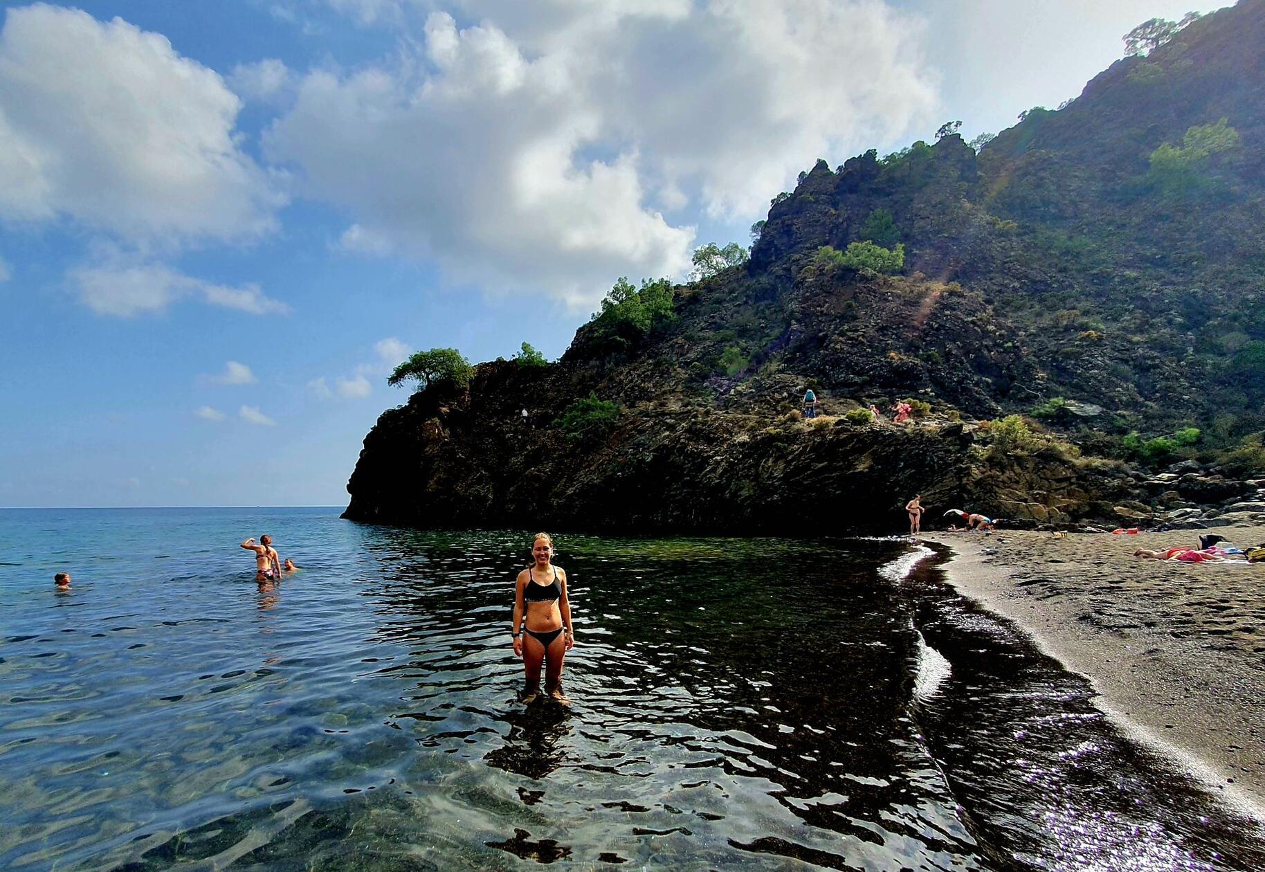 Im schwarzen Sand mit weißen Steinen macht das Bad besonders viel Spaß.