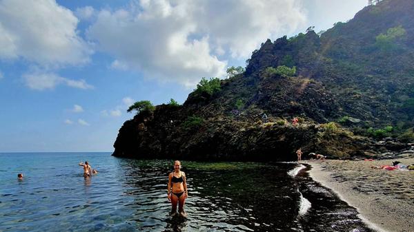 Im schwarzen Sand mit weißen Steinen macht das Bad besonders viel Spaß.