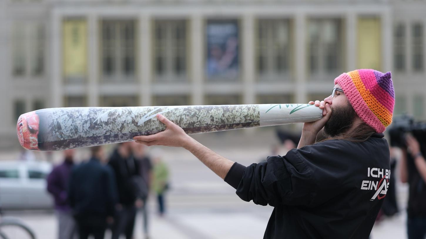 Ein Teilnehmer einer Kundgebung hält einen überdimensionierten Joint in den Händen. Ab dem 1. April 2024 ist Erwachsenen ab 18 Jahren der Besitz von 25 Gramm im öffentlichen Raum erlaubt.