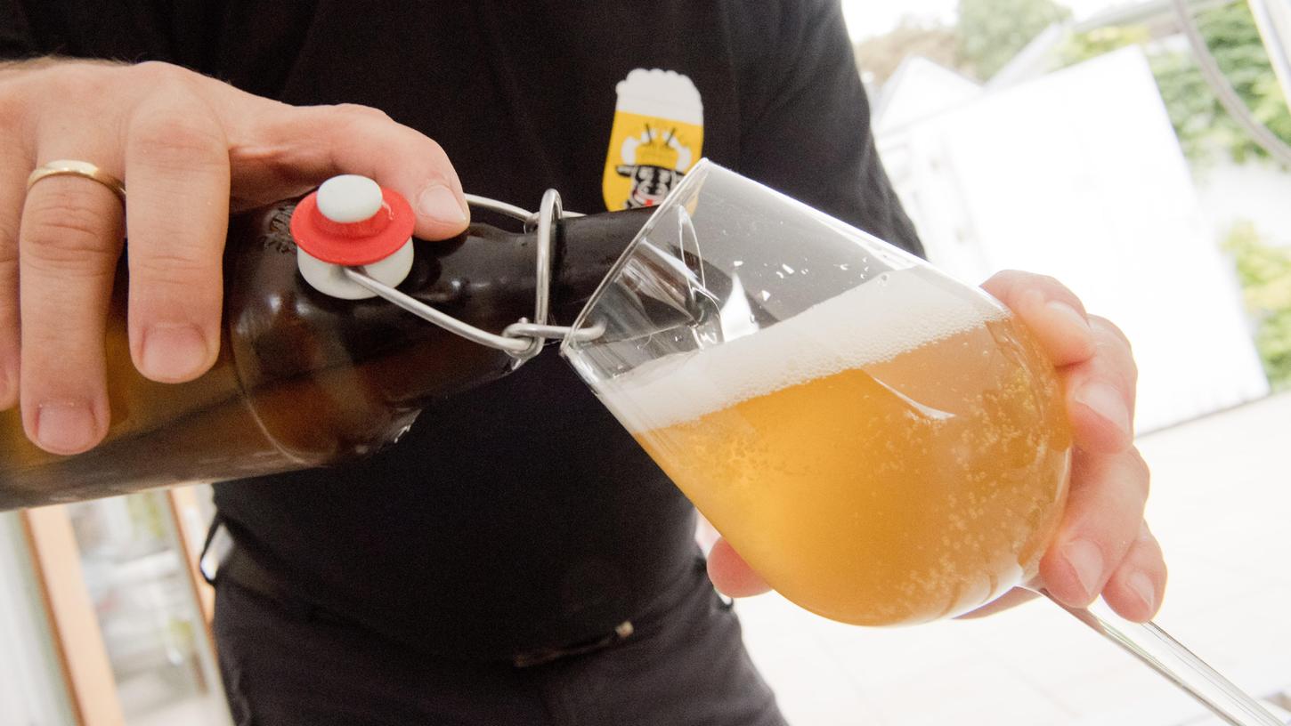 Ein Mann schüttet ein selbstgebrautes Bier in ein Glas. 