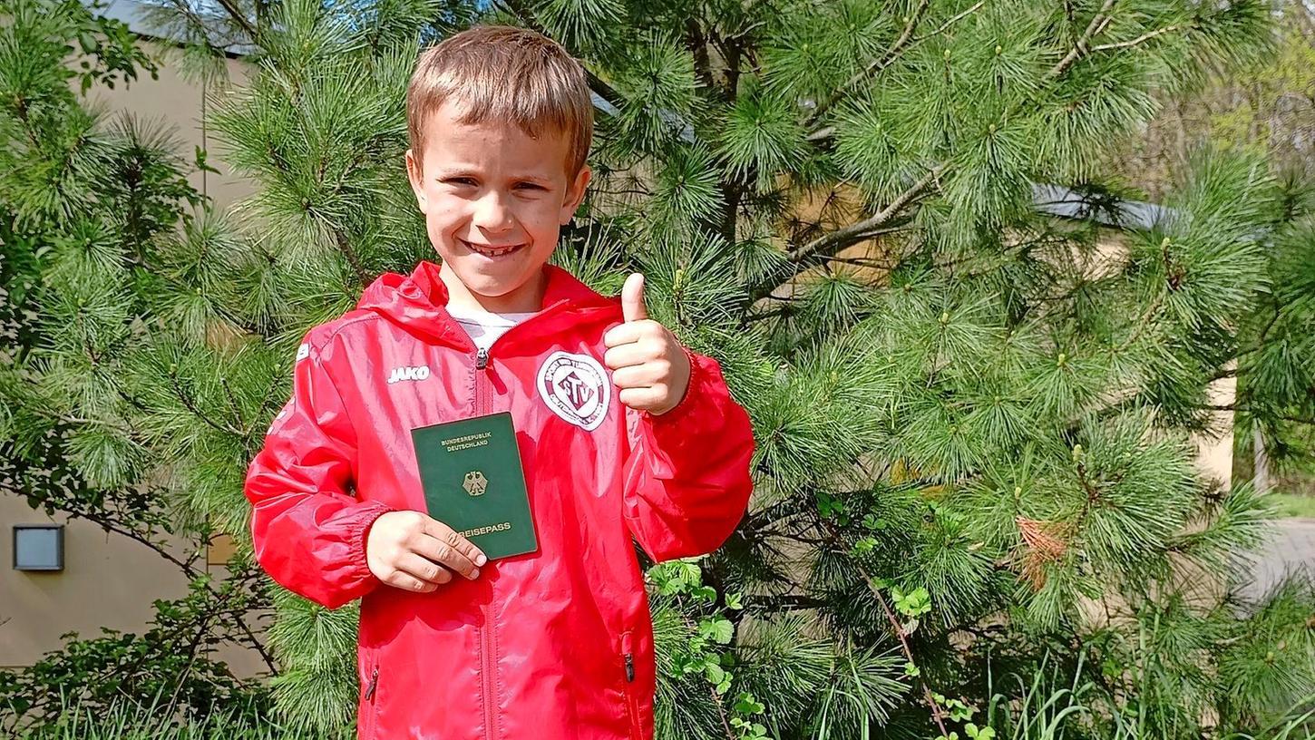 Glücklich hält der Siebenjährige Mischa seinen vorläufigen Reisepass in die Kamera.