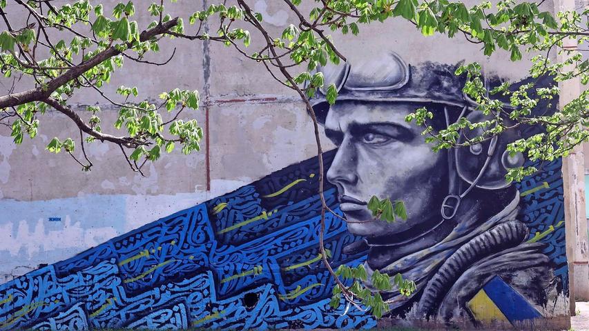 Ein Graffiti auf der Wand eines Wohnblocks zeigt einen ukrainischen Soldaten. Die Ukraine ist angesichts des russischen Angriffskrieges auf Waffenhilfe aus dem Westen angewiesen.