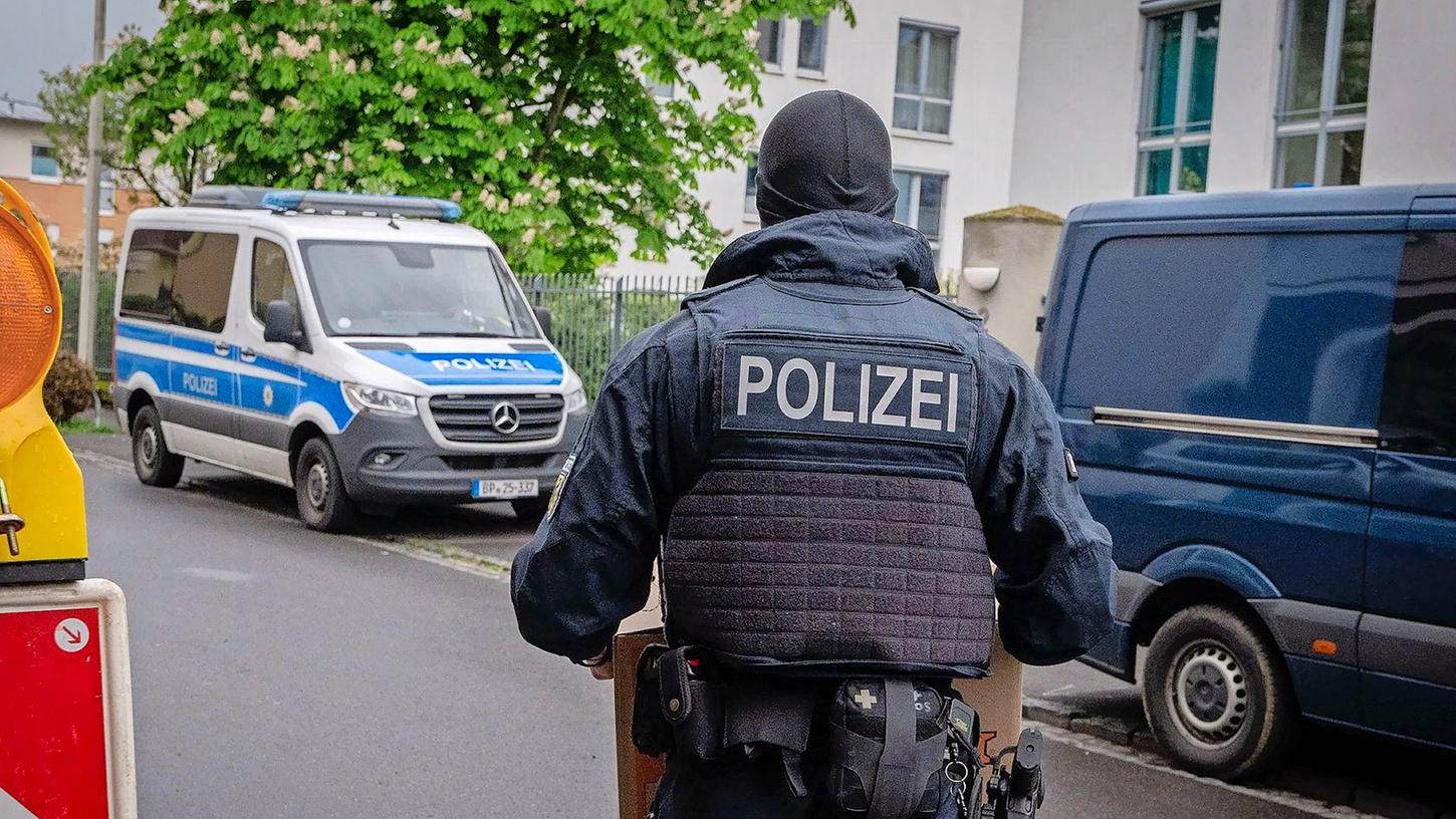 Ein Polizist trägt bei einem Einsatz in Bonn einen Karton mit beschlagnahmtem Material aus einem Gebäude.