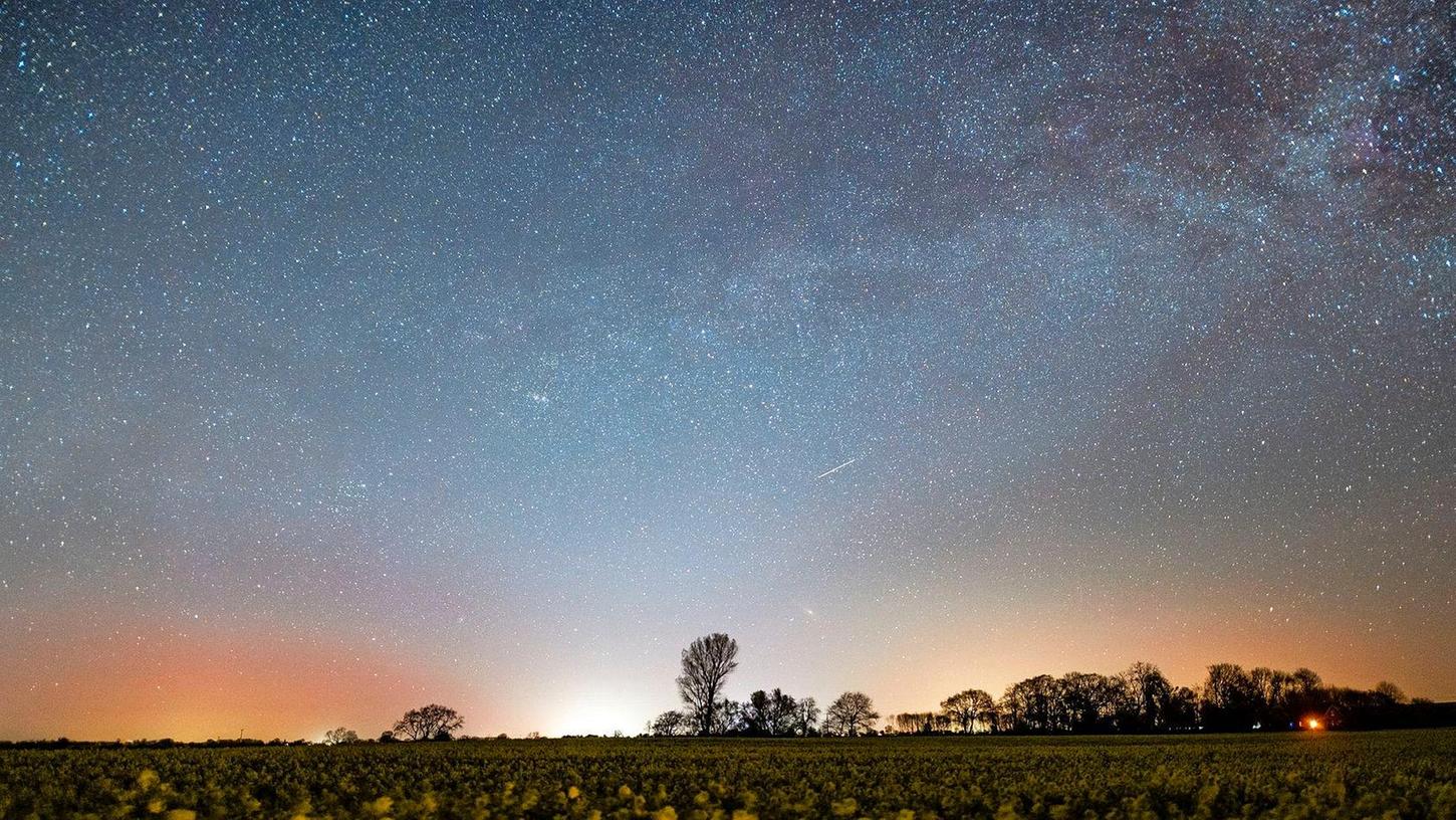 Der Sternenhimmel leuchtet über einem Rapsfeld in Schleswig-Holstein.
