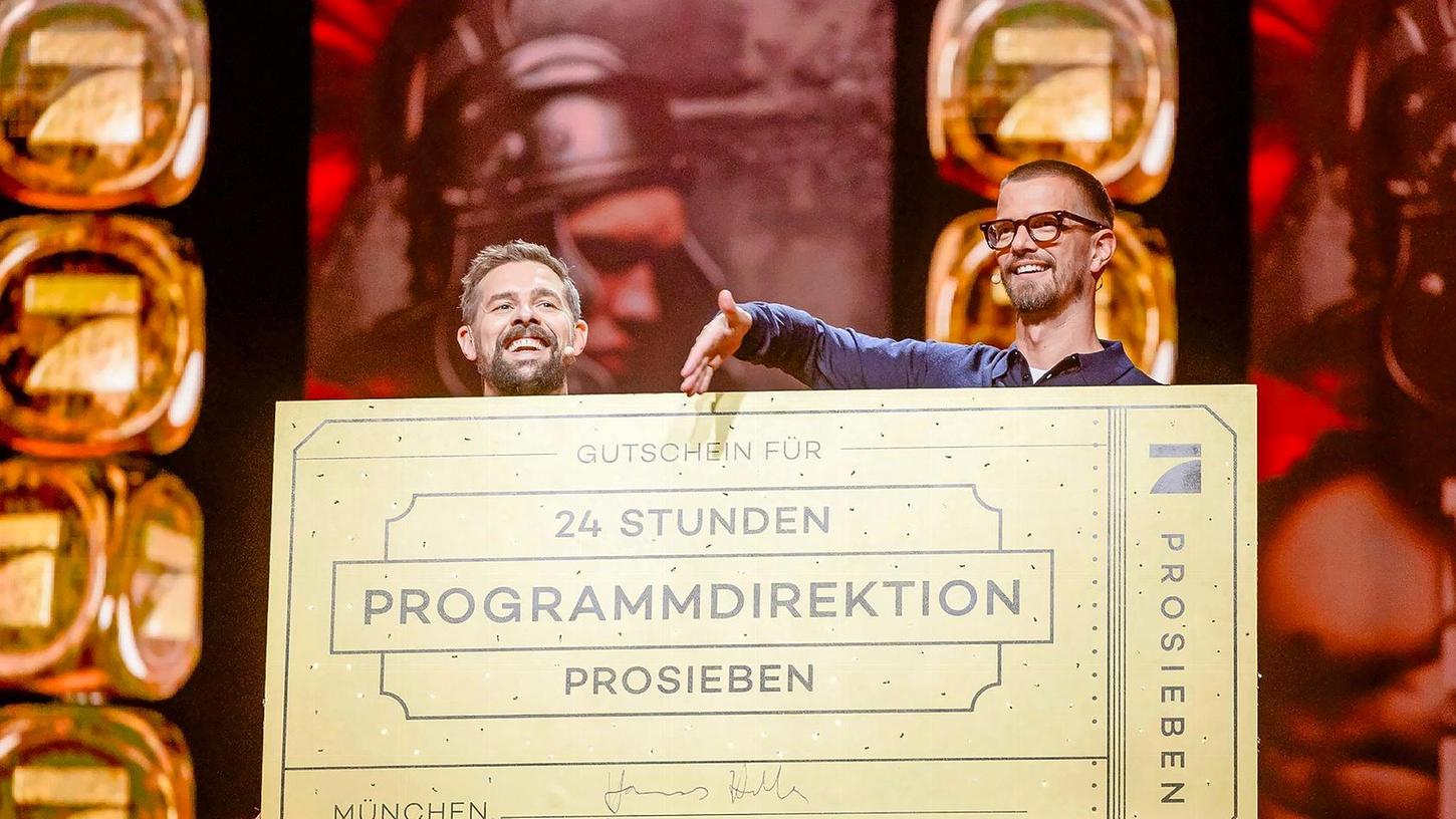 Klaas Heufer-Umlauf (l) und Joko Winterscheidt hinter einem Schild mit der Aufschrift "Gutschein für 24 Stunden Programmdirektion ProSieben".