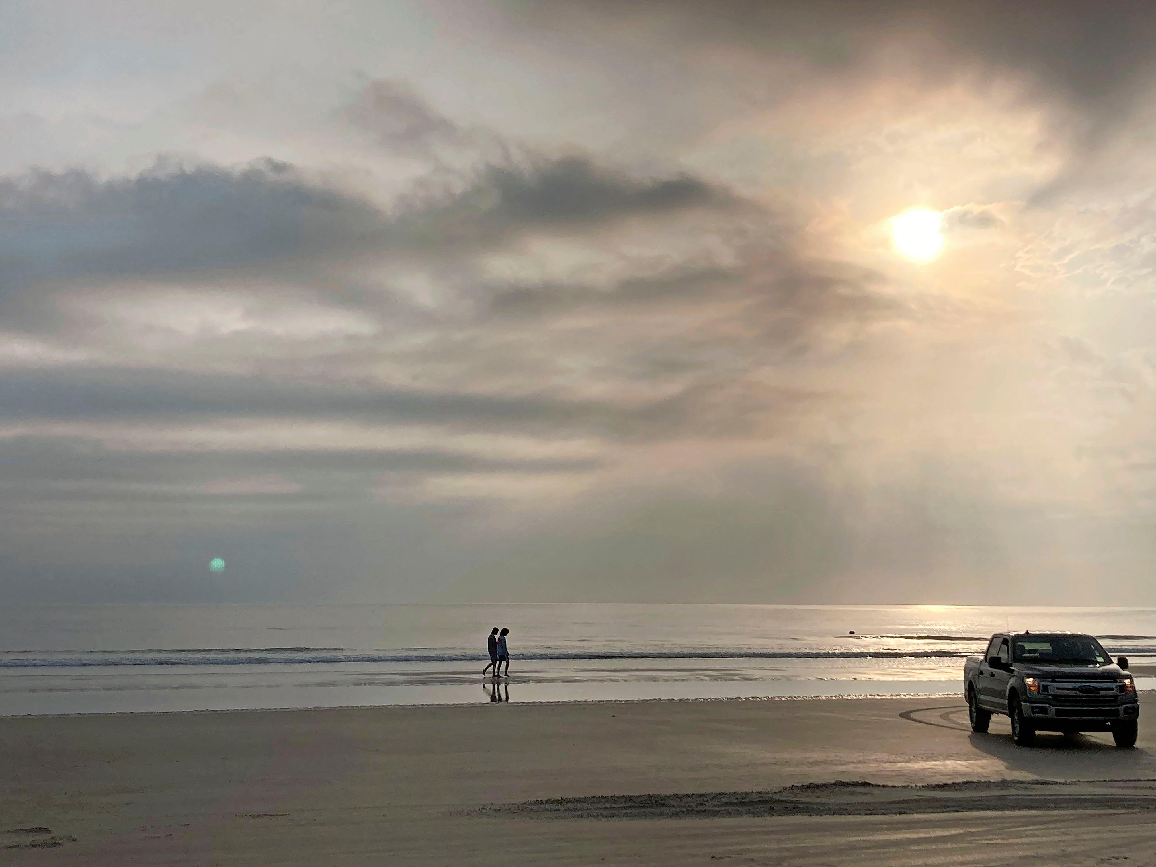 Willkommen in Amerika: Am Strand sind nicht nur E-Bikes, sondern selbst Autos erlaubt: Nur wenige Meter von den Badegästen entfernt rollen Pick-up-Trucks den Sand entlang.