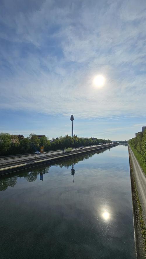 Der Fernmeldeturm spiegelt sich im Wasser des Main-Donau-Kanals. Die Sonne macht es ihm nach.