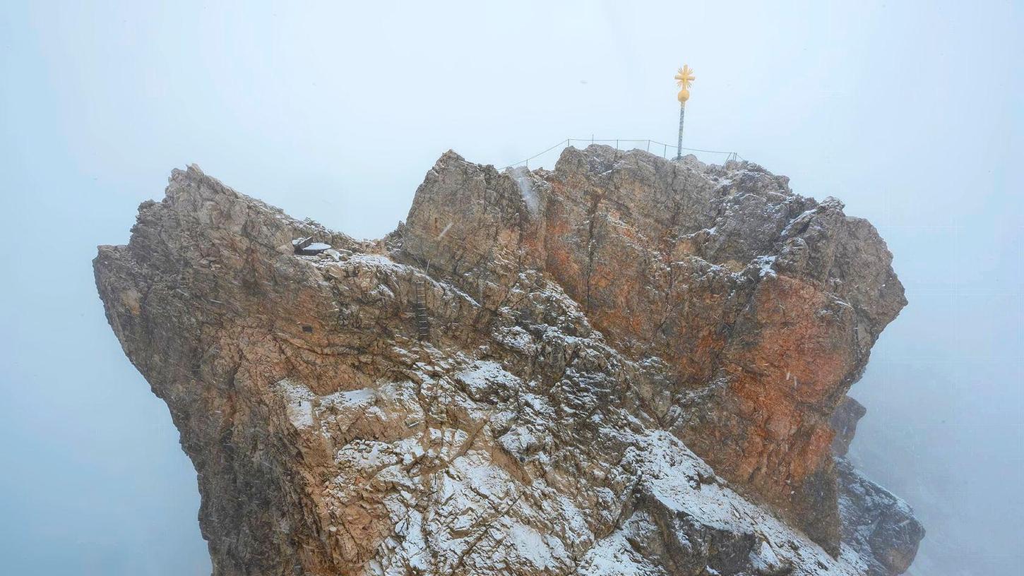 Nebelwolken umhüllen bei Schneetreiben auf der Zugspitze (2962 Meter) die verschneite Aussichtsplattform mit dem Gipfelkreuz.