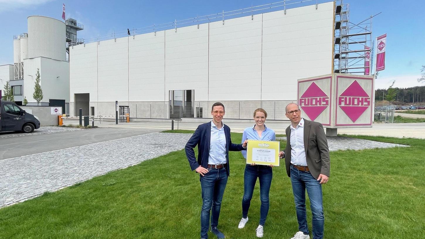 Christoph Bosch, Nancy Fürst und Geschäftsführer Jürgen Joos präsentieren vor der künftigen Produktionsstätte den Innovations-Award.