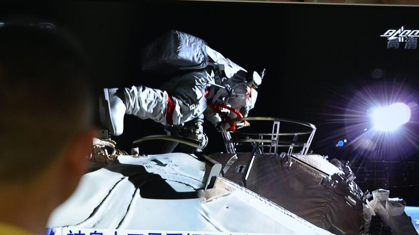 Ein Mann verfolgt vor dem Fernseher die Live-Übertragung eines Außeneinsatzes an der Raumstation "Tiangong" (Archivbild).
