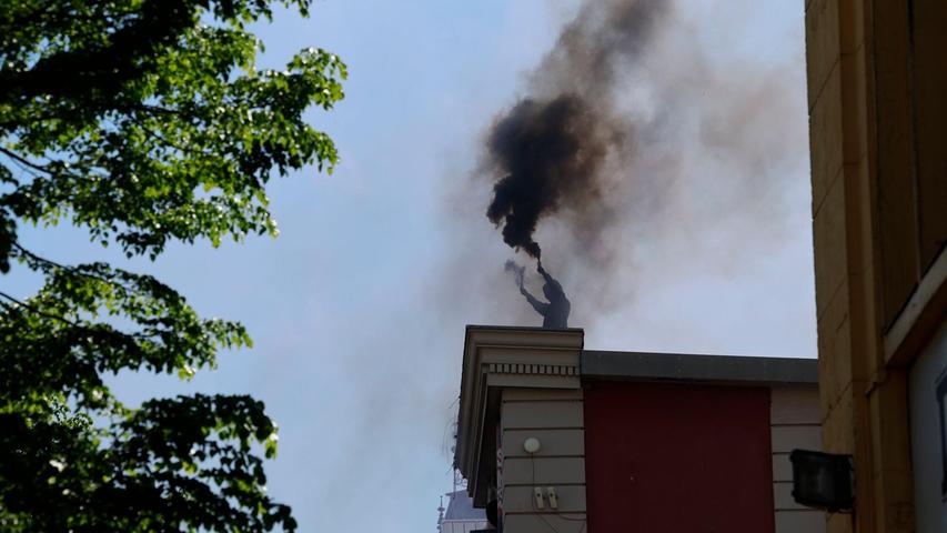 Ein Vermummter brennt auf dem Dach der Roten Flora in Hamburg Pyrotechnik ab.