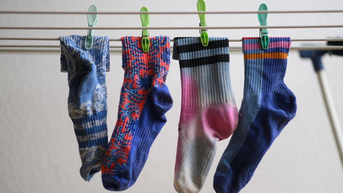 Bunte Socken hängen auf einem Wäscheständer. Am 9. Mai ist Tag der verschwundenen Socken.