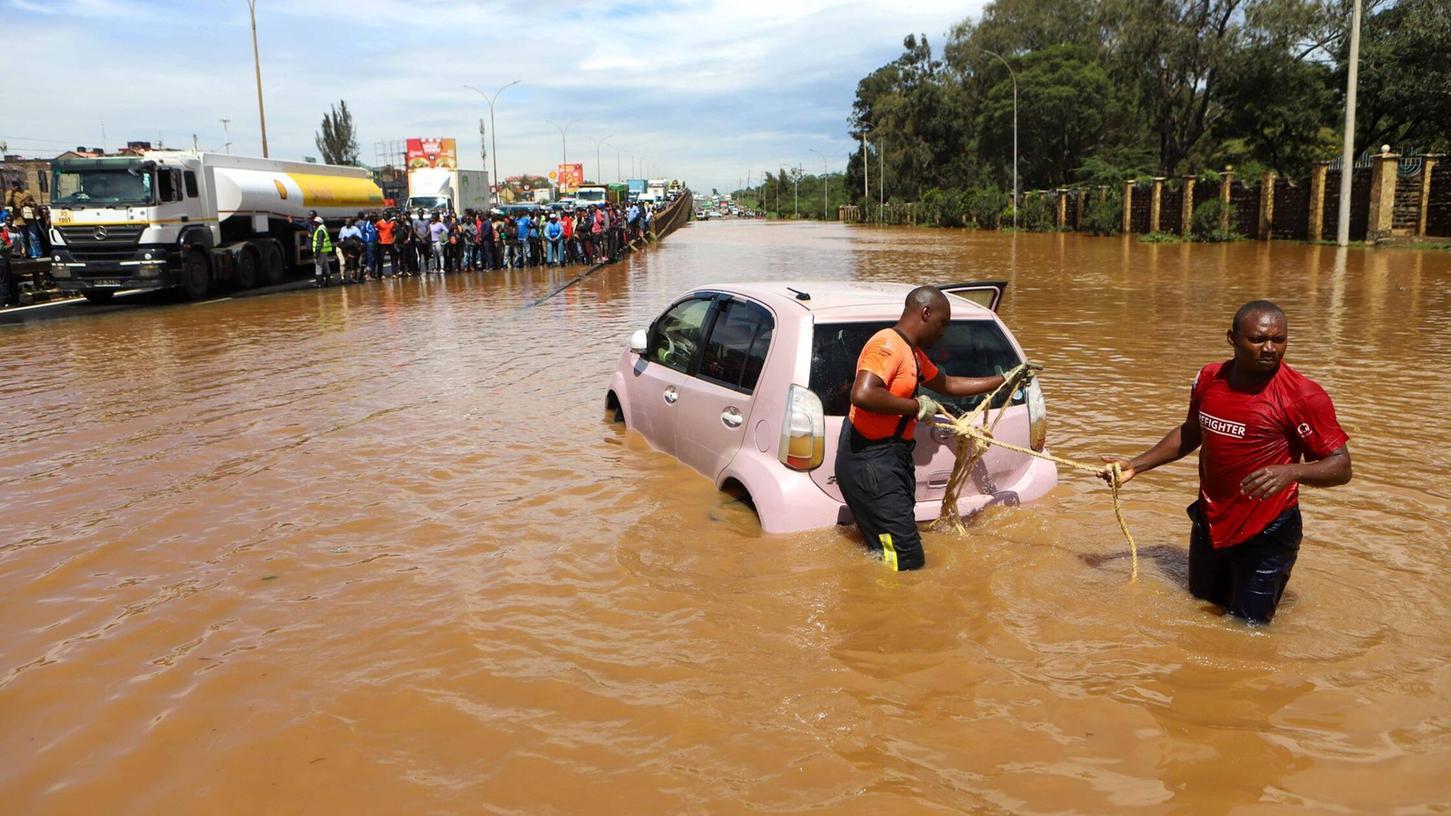 Menschen in Nairobi, die im Hochwasser ein Auto ziehen.