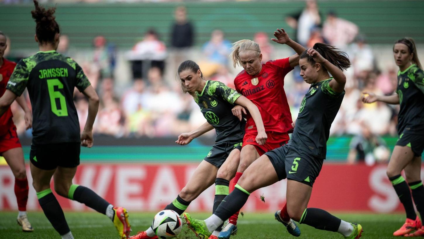 Wolfsburgs Jule Brand (l) und Lena Oberdorf kämpfen mit Bayerns Pernille Harder um den Ball.