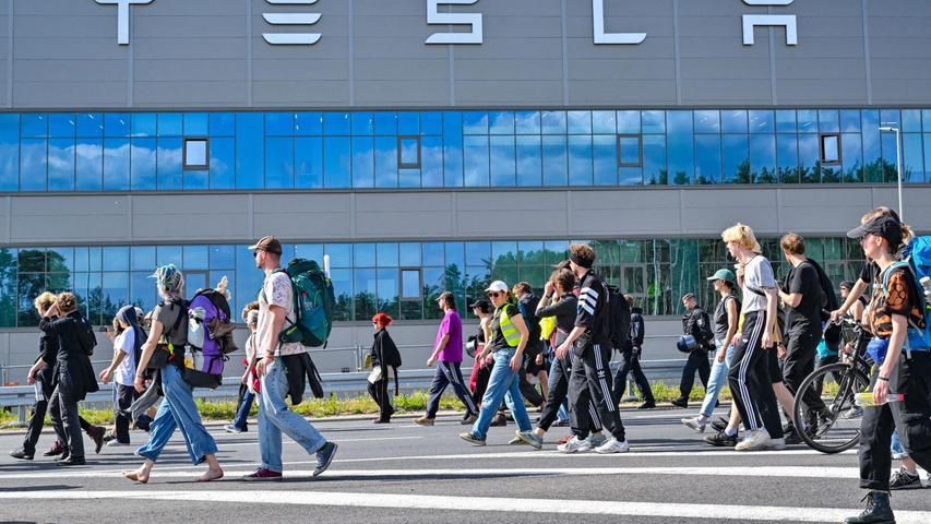 Teilnehmerinnen und Teilnehmer eines Protestmarschs laufen am Tesla-Werk vorbei.