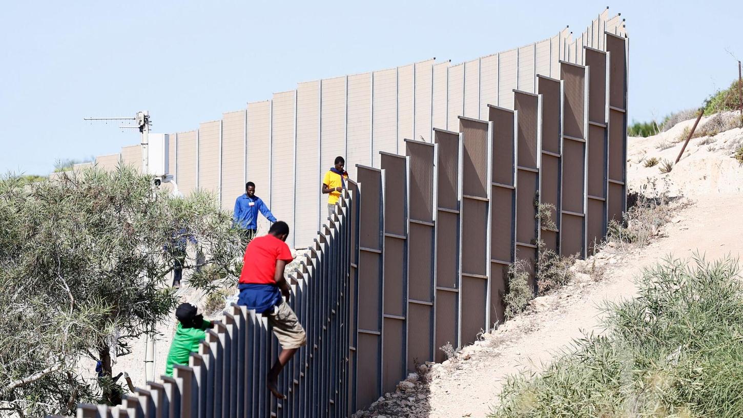 Migranten klettern über einen Zaun auf der italienischen Insel Lampedusa.