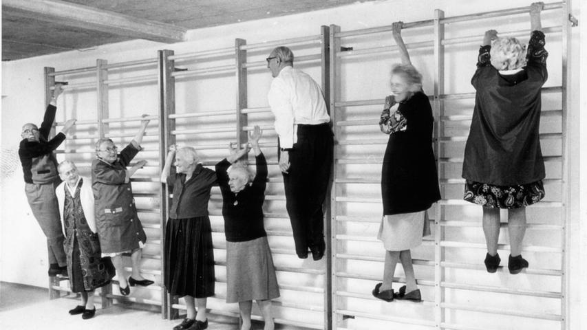 Seniorensport im Jahre 1972: Im Julius-Bauer-Heim am Thoner Weg, welches später durch das Hephata Pflegezentrum in Schafhof ersetzt wurde, stand alles im Zeichen der Rehabilitation. Die Bewohner sollten wieder fit für einen selbstständigen Alltag gemacht werden. Hierfür verfügte das Haus über Bäder, Massagen und Bewegungstherapie-Angebote, auch die hier abgebildete Sprossenwand gehörte dazu. Zum Teil mit sichtlichem Spaß erklommen die betagten Sportler und Sportlerinnen das Holzgerüst. Auch ein Bierstüberl mit Kegelbahn sollte Aktivität und Wohlbefinden steigern, leider ist uns hierzu jedoch kein Bildmaterial überliefert. Seniorensport im Jahre 1972: Im Julius-Bauer-Heim am Thoner Weg, welches später durch das Hephata Pflegezentrum in Schafhof ersetzt wurde, stand alles im Zeichen der Rehabilitation. Die Bewohner sollten wieder fit für einen selbstständigen Alltag gemacht werden. Hierfür verfügte das Haus über Bäder, Massagen und Bewegungstherapie-Angebote, auch die hier abgebildete Sprossenwand gehörte dazu. Zum Teil mit sichtlichem Spaß erklommen die betagten Sportler und Sportlerinnen das Holzgerüst. Auch ein Bierstüberl mit Kegelbahn sollte Aktivität und Wohlbefinden steigern, leider ist uns hierzu jedoch kein Bildmaterial überliefert.
