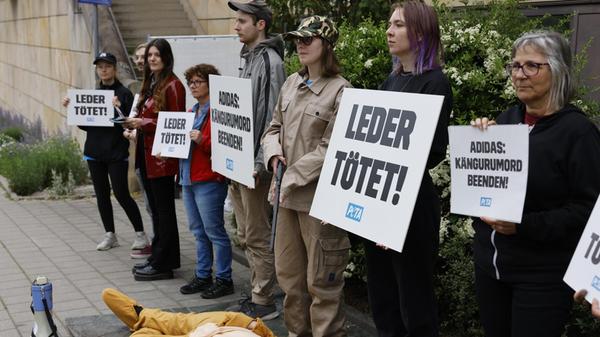 Auf ihren Plakaten und Schildern skandierten die Peta-Demonstranten zum Beispiel "Leder tötet" oder "Adidas: Kängurumord beenden!". Zur Symbolisierung und Untermauerung lag das Fake-Känguru reg- und leblos zu den Füßen der Protestierenden.