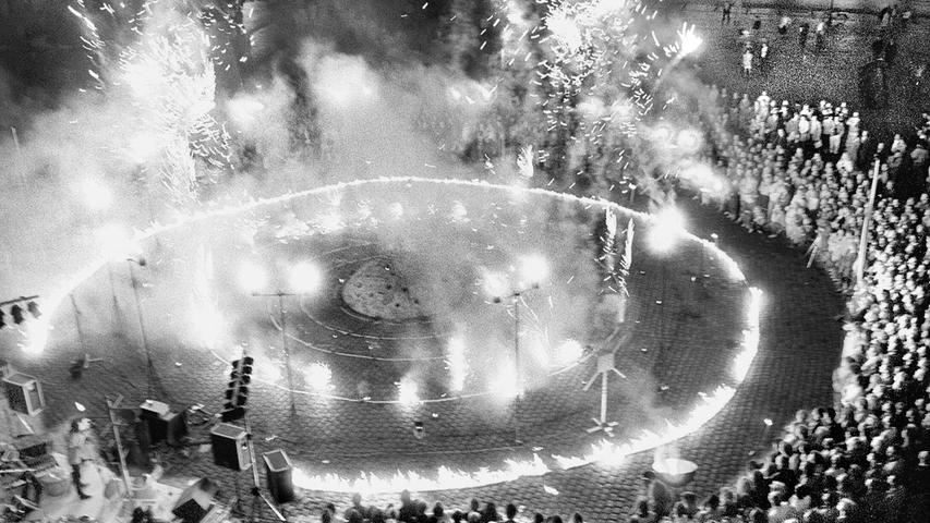 „Moonlanding und Blaukraut“ war der Titel dieser pyrotechnischen Schau von Götz Schwörer. Am 23.6.1990 eröffnete er damit fulminant die Ausstellung „Zehnvorzweitausend“ der Künstlergruppe „Der Kreis“ auf dem Hauptmarkt in Nürnberg. Das Feuerspektakel untermalte ein Percussionist mit wildem Hämmern auf Alltagsmaterial wie Waschmaschinentrommeln und metallenen Kleiderständern. Als die Schwefelschwaden abgezogen waren, konnten die Zuschauer den Kunst-Parcours, der direkt zwischen den Marktständen aufgebaut war, erkunden. Zehn Tage lang sorgten die Skulpturen und Installationen zwischen Obst und Gemüse für Kontroversen. „Moonlanding und Blaukraut“ war der Titel dieser pyrotechnischen Schau von Götz Schwörer. Am 23.6.1990 eröffnete er damit fulminant die Ausstellung „Zehnvorzweitausend“ der Künstlergruppe „Der Kreis“ auf dem Hauptmarkt in Nürnberg. Das Feuerspektakel untermalte ein Percussionist mit wildem Hämmern auf Alltagsmaterial wie Waschmaschinentrommeln und metallenen Kleiderständern. Als die Schwefelschwaden abgezogen waren, konnten die Zuschauer den Kunst-Parcours, der direkt zwischen den Marktständen aufgebaut war, erkunden. Zehn Tage lang sorgten die Skulpturen und Installationen zwischen Obst und Gemüse für Kontroversen.