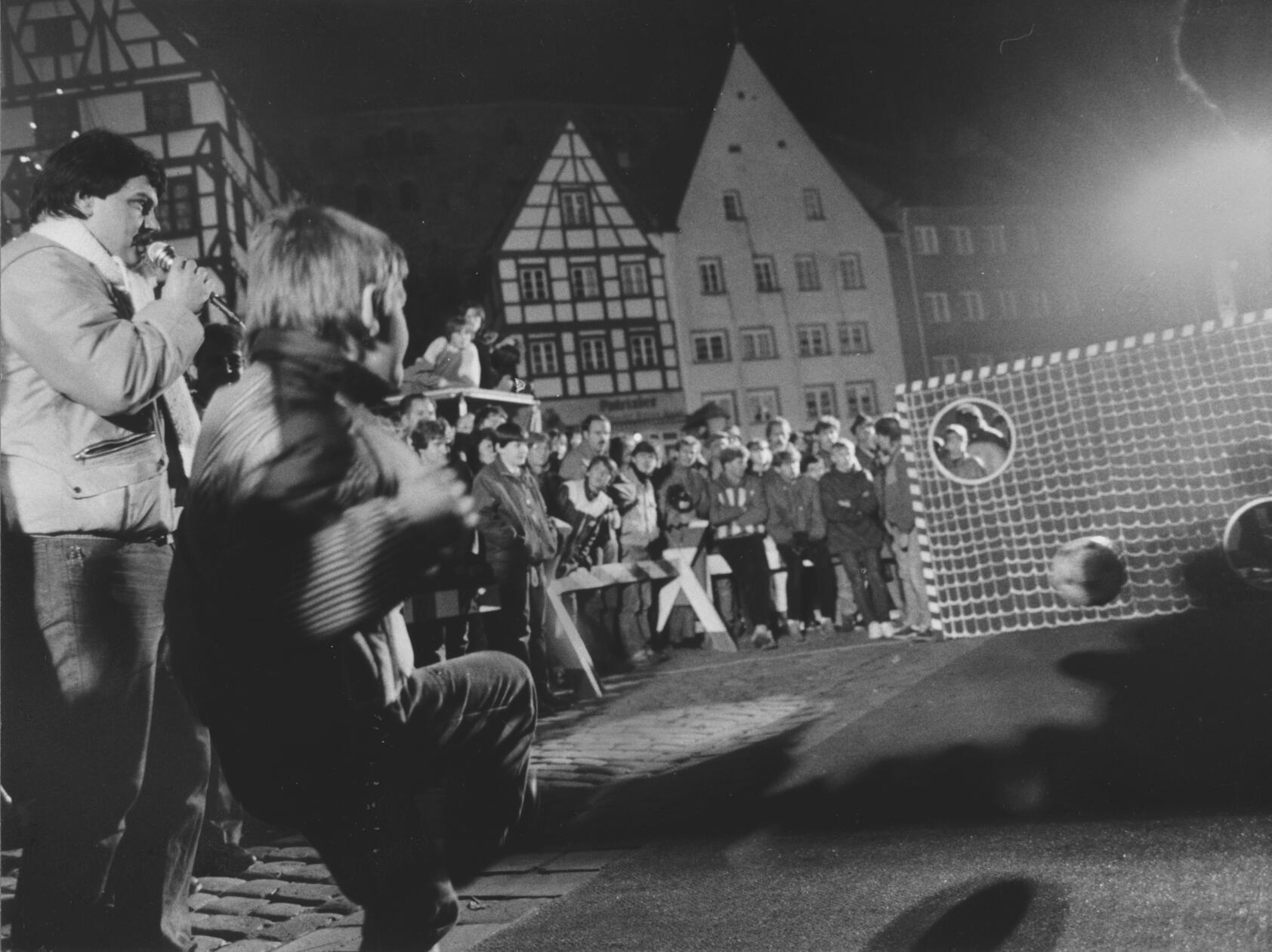 Am 1. Dezember 1984 stand der Tiergärtnertorplatz ganz im Zeichen des Fußballs: Das ZDF-Sportstudio gastierte mit seiner Torwand in Nürnberg. Nachdem sich eine Stunde lang die Kinder an der Wand probieren durften (unser Foto), wurde es ernst: Unter über 100 Teilnehmern galt es, den besten für das Duell mit dem damaligen HSV-Spieler Felix Magath herauszufinden. Im Stechen qualifizierte sich schließlich der 16jährige Oliver Schwan vom VfL Nürnberg mit vier Treffern. Als er dann live gegen Magath antreten durfte, schoss er den Ball noch zweimal erfolgreich durch die Torwand, was ihm überraschenderweise den Sieg bescherte.
