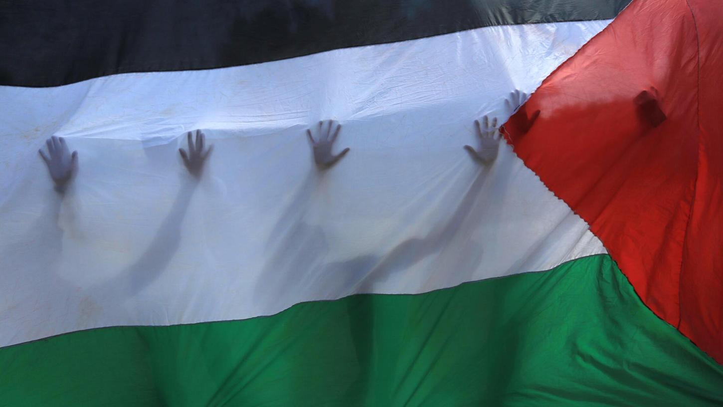 Protest für Palästina: Demonstrierende sind durch eine palästinensische Flagge zu erkennen.