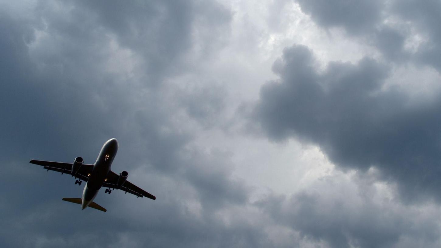 Gewitterwolken türmen sich über einem Flugzeug auf.