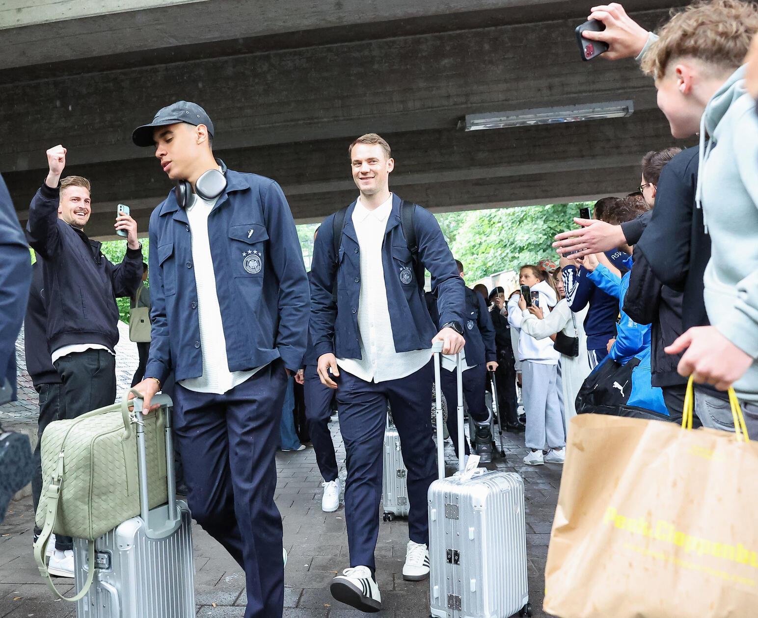 Die Nationalspieler Jamal Musiala (2.v.l.) und Torhüter Manuel Neuer (Mitte) gehen bei der Ankunft am Bahnhof an Fans vorbei.
