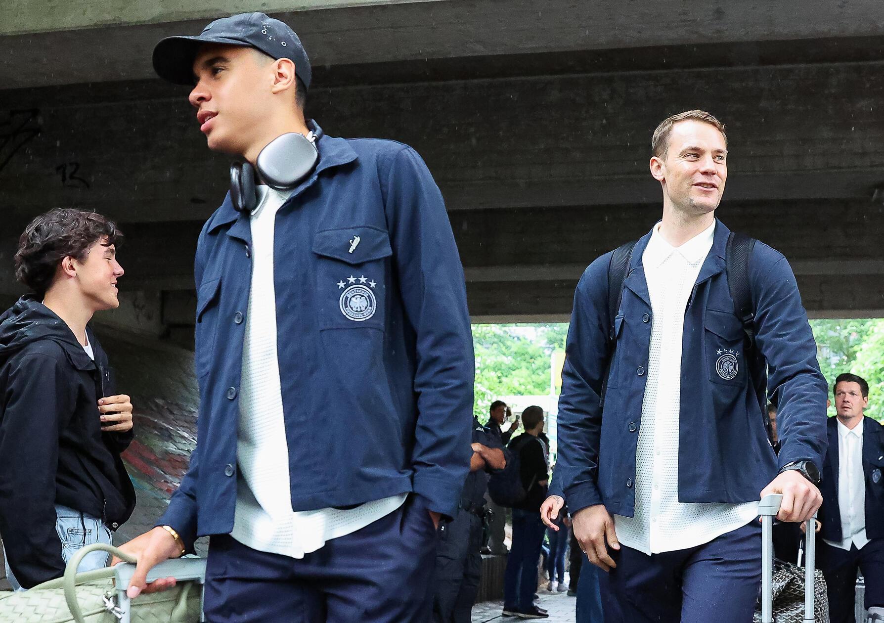 Die Nationalspieler Jamal Musiala (l.) und Torhüter Manuel Neuer gehen bei der Ankunft am Bahnhof an Fans vorbei.