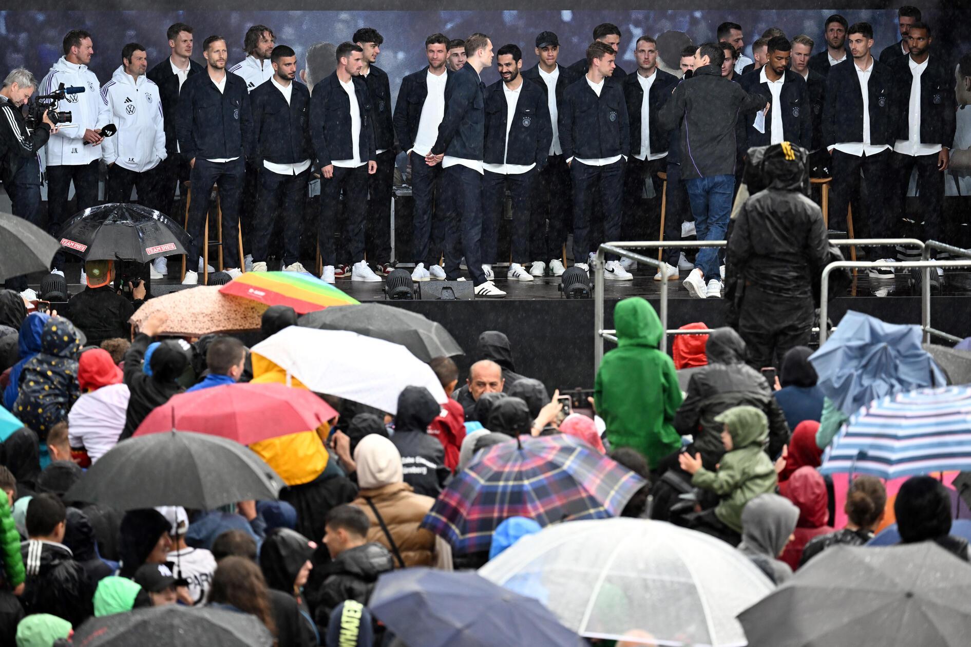 Jede Menge bunte Regenschirme: Die Nationalmannschaft wird bei Regenwetter von zahlreichen Fans begrüßt.