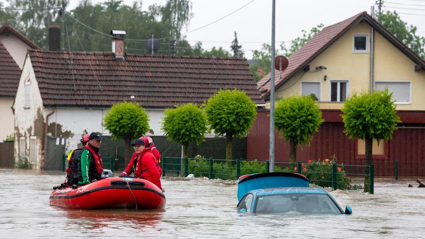 Die Wasserwacht fährt mit einem Schlauchboot durch eine überflutete Straße in Babenhausen im Unterallgäu. Auch in Burgwalden und seinen Ortsteilen müssen Anwohner mit Hubschrauber und Booten evakuiert werden.